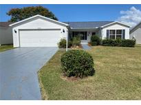 White single-story house with a two-car garage and landscaped lawn at 2707 Privada Dr, The Villages, FL 32162