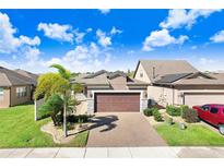 Two-story home with brick facade, 2-car garage, and landscaped yard at 251 Tomelloso Way, Davenport, FL 33837