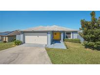 Cute one-story home with a yellow door, attached garage, and well-maintained lawn at 612 Chicago Way, Dundee, FL 33838
