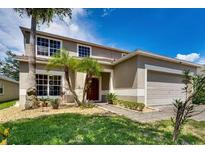 Two-story house with a beige exterior, landscaped yard, and a two-car garage at 4615 Cumbrian Lakes Dr, Kissimmee, FL 34746