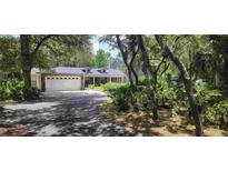 Two-story home with a large driveway and mature landscaping at 14815 Lake Pickett Rd, Orlando, FL 32820