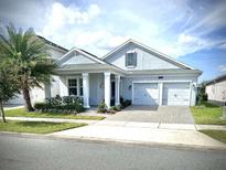 Two story house with light blue exterior, two car garage, and landscaping at 4552 Sequel Rd, Kissimmee, FL 34746