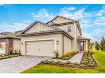Two-story house with beige siding, gray-stone driveway, and landscaped front yard at 7737 Somersworth Dr, Kissimmee, FL 34747