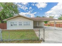 Tan house with carport, fenced yard, and mature trees at 910 N Lincoln Ave, Lakeland, FL 33815