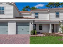 Two-story townhome with light gray siding, two-car garage, and landscaped front yard at 576 Bay Leaf Dr, Poinciana, FL 34759