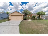 Tan house with a two-car garage and well-maintained lawn at 3301 Enclave Blvd, Mulberry, FL 33860