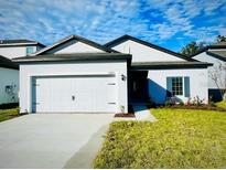 Two-car garage and landscaped lawn at 13473 Leaping Water Way, Astatula, FL 34705