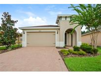 Beige one-story home with arched entryway and attached two-car garage at 1423 Harbor Ridge Dr, Poinciana, FL 34759