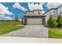 Inviting two-story home with a paved driveway, stone accents, and a two-car garage at 7837 Somersworth Dr, Kissimmee, FL 34747