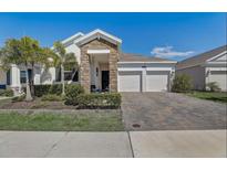 Attractive single-story home with a stone and stucco facade, paver driveway, and lush landscaping at 1767 Bee Nice Dr, Kissimmee, FL 34744