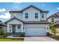 Charming two-story home with a light blue and gray exterior, a paved driveway, and a two-car garage at 7865 Somersworth Dr, Kissimmee, FL 34747