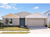One-story house with gray siding, beige garage door, and teal front door at 1106 Foreshore Ln, Haines City, FL 33844