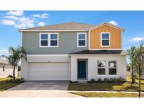 Two-story house with gray and orange siding, white garage door, and teal front door at 725 Ambleside Dr, Haines City, FL 33844