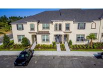 Tan, two-story townhome with gray roof, two-car driveway, and landscaping at 1534 Carey Palm Cir, Kissimmee, FL 34747