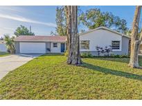 Ranch style home with a white and gray exterior, nicely landscaped lawn, and a two-car garage at 618 El Camino Real S, Lakeland, FL 33813