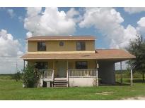 Two-story yellow house with a brown roof, front porch, and yard at 600 Mosley Rd, Fort Meade, FL 33841