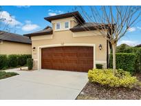 Tan house with brown garage door, landscaping, and walkway at 3124 Bailey Ann Dr, Ormond Beach, FL 32174