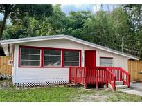 Cozy ranch-style home with red accents and a wooden deck at 150 E Washington Ave, Lake Helen, FL 32744