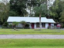 Single story home with metal roof and fenced yard at 24008 Ermine Rd, Astor, FL 32102