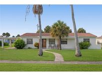 Charming single story home with red tile roof, lush lawn, and palm trees at 133 Cardinal Dr, Ormond Beach, FL 32176