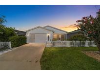 White single story home with attached garage, and white picket fence at 1106 Carvello Dr, The Villages, FL 32162