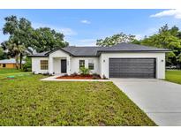 New construction home with a modern design and dark garage door at 210 E Baxter St, De Leon Springs, FL 32130