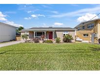 Tan brick home with red door, spacious lawn, and mature landscaping at 505 Wisteria Rd, Daytona Beach, FL 32118