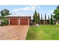 Red two-car garage home with brick driveway and landscaped yard at 980 Bluebird Ter, Deltona, FL 32725