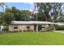 Brick ranch home with well-manicured lawn and American flag at 1040 Tappan Cir, Orange City, FL 32763