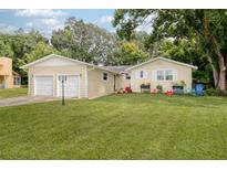Two-car garage, light beige exterior, and nicely landscaped lawn at 246 Angeles Rd, Debary, FL 32713