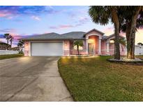 Pink house with a white garage door and landscaped lawn at 7 Sea Park Ter, Ormond Beach, FL 32176