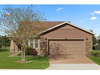 Single-story home with a brown exterior, two-car garage, and well-manicured lawn at 4747 Nw 35Th Lane Rd, Ocala, FL 34482