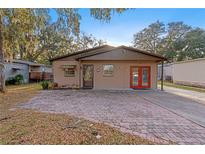 Tan single story home with brick paver driveway and landscaped yard at 6 Rosalie Oaks Blvd, Lake Wales, FL 33898