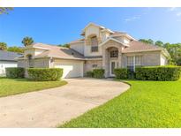 Two-story brick home with a large front yard, driveway, and mature landscaping at 6180 Knotty Pine Ct, Port Orange, FL 32127