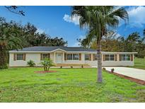 Newly constructed home with a light beige exterior, wood accents, and a spacious lawn at 1518 Lakeside Dr, Deland, FL 32720