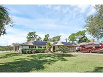 Single-story home with solar panels, RV parking, and a lush lawn at 422 N Pine Meadow Dr, Debary, FL 32713