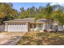 Cute one-story house with a white garage door and a palm tree in the front yard at 1281 W New York Ave, Orange City, FL 32763