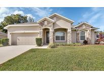 Tan house with stone accents and a two-car garage at 704 Ostrich Fern Ln, Deland, FL 32720