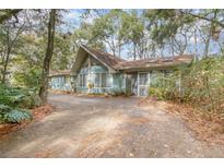 Charming blue home nestled among trees with a brick driveway at 855 E Church St, Deland, FL 32724