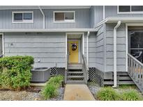 Gray siding townhouse with yellow door, steps, and landscaping at 2329 River Ridge Rd # 13, Deland, FL 32720