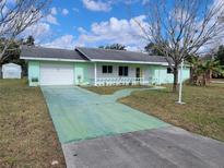 Ranch-style home with a green exterior, attached garage, and a long driveway at 525 E Roberts St, Orange City, FL 32763