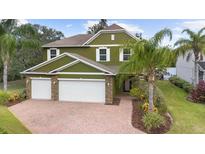 Green house with two-car garage, landscaping, and palm trees at 732 Wildmere Village Cv, Longwood, FL 32750