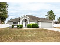 One-story house with gray siding, attached garage, and well-manicured lawn at 90 Dogwood Drive Cir, Ocala, FL 34472