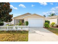 Tan house with white picket fence, attached garage, and landscaped yard at 1052 Ridgeville Rd, The Villages, FL 32162