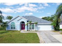 Blue house with a red door, gray roof, and a two-car garage at 12450 Greco Dr, Orlando, FL 32824