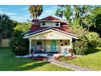 Charming yellow house with red roof, porch, and landscaped yard at 104 Sunset Way, Fruitland Park, FL 34731