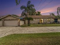 Ranch style home with stone exterior, attached garage, and a spacious driveway at 1910 E Pollock Rd, Lakeland, FL 33813