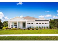 White one-story house with a two-car garage, rocking chairs on the porch, and manicured lawn at 7304 Sw 107Th Ln, Ocala, FL 34476