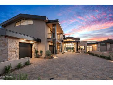 Modern home with stone and stucco exterior, large driveway, and landscaping at 38152 N 109Th St, Scottsdale, AZ 85262