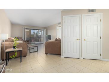 Living room with brown sofas and access to balcony at 17404 N 99Th Ave # 339, Sun City, AZ 85373